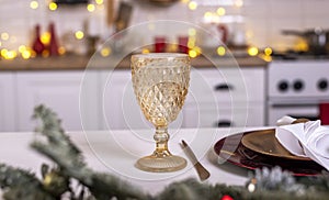 Yellow glass for wine over blurred background of kitchen decorated for christmas with lights