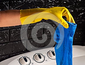 yellow gloved hands in a blue sock near a white washing machine