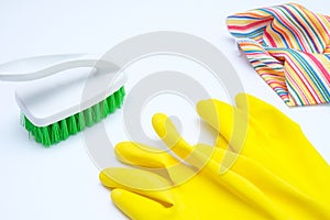 Yellow gloves with a green brush and microfiber wipe on white background, cleaning home and routine work concept