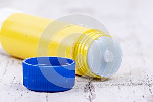 Yellow glue stick with blue lid on rustic white wood