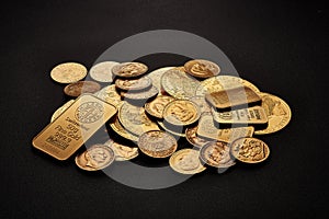 Yellow gold bars and coins isolated on black background