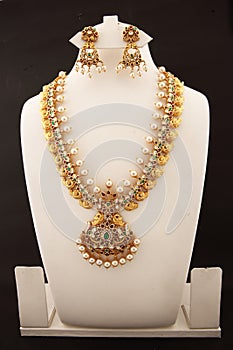 yellow gold choker necklace with matching earrings with hanging pearls on a white background.