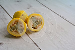 Yellow or golden passion fruit, whole and cut, on timber background