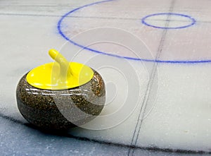 Yellow granite stone for curling game on the ice