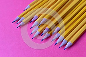 Yellow graphite pencils on a pink background