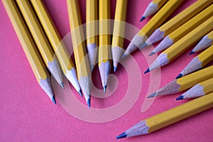 Yellow graphite pencils on a pink background