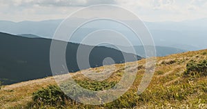 yellow grass in the highlands, swaying in the wind. Stunning view of mountain hills and clouds in the sky