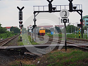 Yellow-gray trains, bridges and tracks, gray-black, orange, green leaves, gray-white sky and white light.