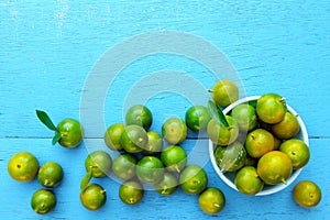 Yellow green calamansi, calamondin or philippine lime tropical fruit pattern in bright blue wood background. Asian summer citrus.