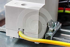 Yellow and green ground wire connected to the electrical socket mounted on DIN rail close-up. Electrical appliance grounding