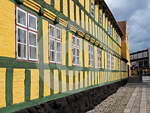 Yellow and green half-timbered building with row of windows