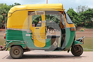 Yellow and green indian auto rickshaw. Yellow and green tuktuk near river photo