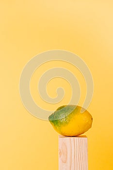 yellow and green lemon on wood pedestal on yellow background