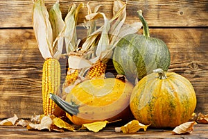 Pumpkins with corn on a wooden background.