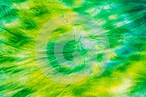 Yellow green spiral tie dye background on fabric. Flat lay.