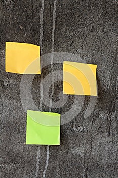 Yellow and green sticky notes on the gray wall