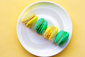 Yellow and green sweet tasty macaroons on the plate.