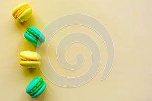 Yellow and green sweet tasty macaroons on yellow background.