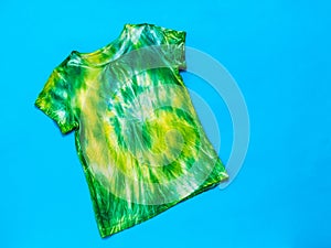 Yellow and green tie dye t-shirt on a bright blue background. Flat lay.