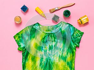 Yellow and green tie dye t-shirt with colors on a red background. Flat lay.