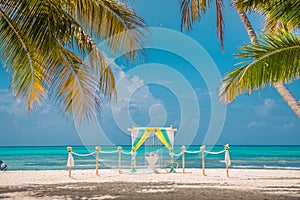 Yellow and green wedding archway are arranged on the sand in preparation for a beach wedding ceremony.