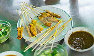 Yellow grilled pork in stick called pork satay in plate with di