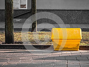 A yellow grit salt box on the street.