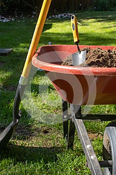 Shovle leaning on a wheelbarrow filled with dirt