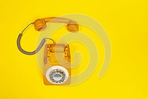 Yellow handset of a telephone on a yellow background.