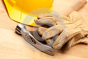 Yellow Hard Hat, Gloves and Hammer on Wood