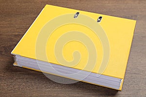Yellow hardcover office folder on wooden table, closeup