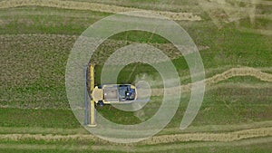 Yellow harvester on the wheat field from the top view. Agriculture food production.