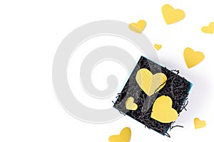 The yellow heart-shaped shapes are cut from cardboard and are on black paper in a gift box.