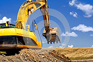 Yellow, heavy duty excavator moving soil and sand