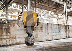 Yellow heavy duty isolated lifting pulley crane hook in industrial engineering tool factory with wire cables and safety clip