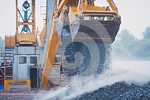 Yellow heavy excavator and bulldozer excavating sand and working during road works, unloading sand and road metal during construct