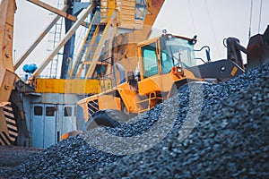 Yellow heavy excavator and bulldozer excavating sand and working during road works, unloading sand and road metal during construct