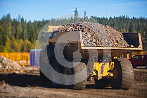 Yellow heavy excavator and dump tip truck tipper excavating sand and working during road works, unloading sand during construction