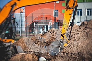 Yellow heavy excavator excavating sand and working during road works, unloading sand during construction of the new road with