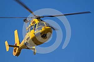 Yellow Helicopter flying in blue sky
