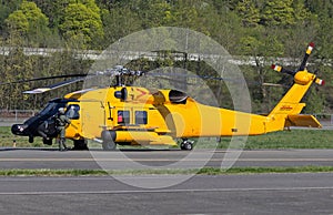 Yellow helicopter sitting on tarmac with crew