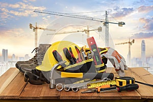 Yellow helmet for construction work and tools with a background crane