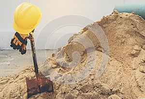 Yellow helmets, gloves and shovel on the sand pile.