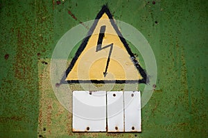 Yellow high voltage sign on aged green wall