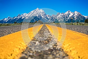 Yellow highway dividing lines with beautiful landscape from Grand Teton National Park