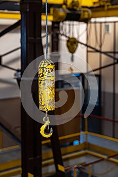 Yellow hook hanged on steel rope inside big hall