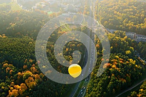 Yellow hot air balloon flying over Vilnius city on sunny autumn evening