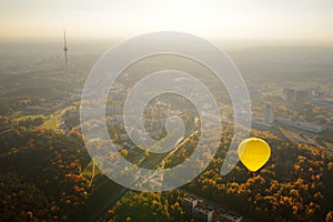 Yellow hot air balloon flying over Vilnius city on sunny autumn evening