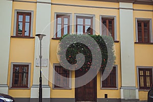 Yellow house with brown windows, wooden door, grey roof and car in front of it