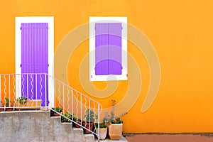 Yellow house front with purple shuttered door and window